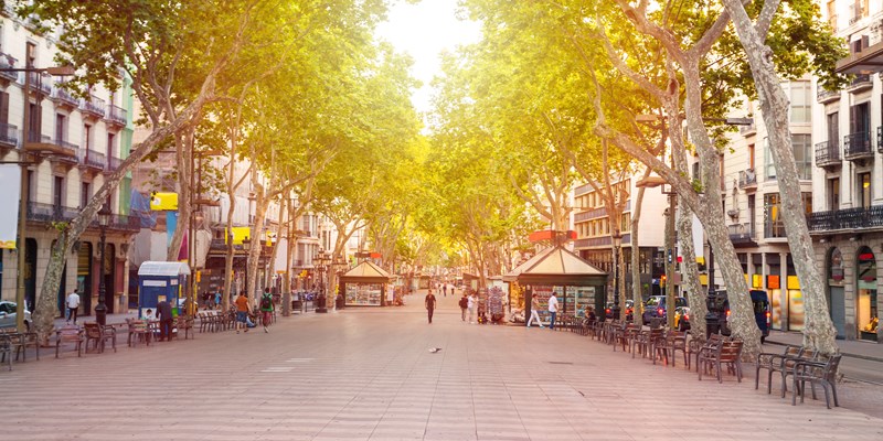 La Rambla pedestrian street in Barcelona city. Selective focus on drinking water fountain on foreground. La Rambla is popular tourist place in Barcelona, spanish travel photo.