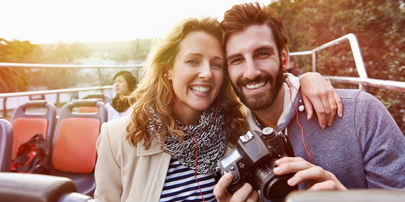 portrait of couple enjoying holiday vacation sightseeing bus open top tour