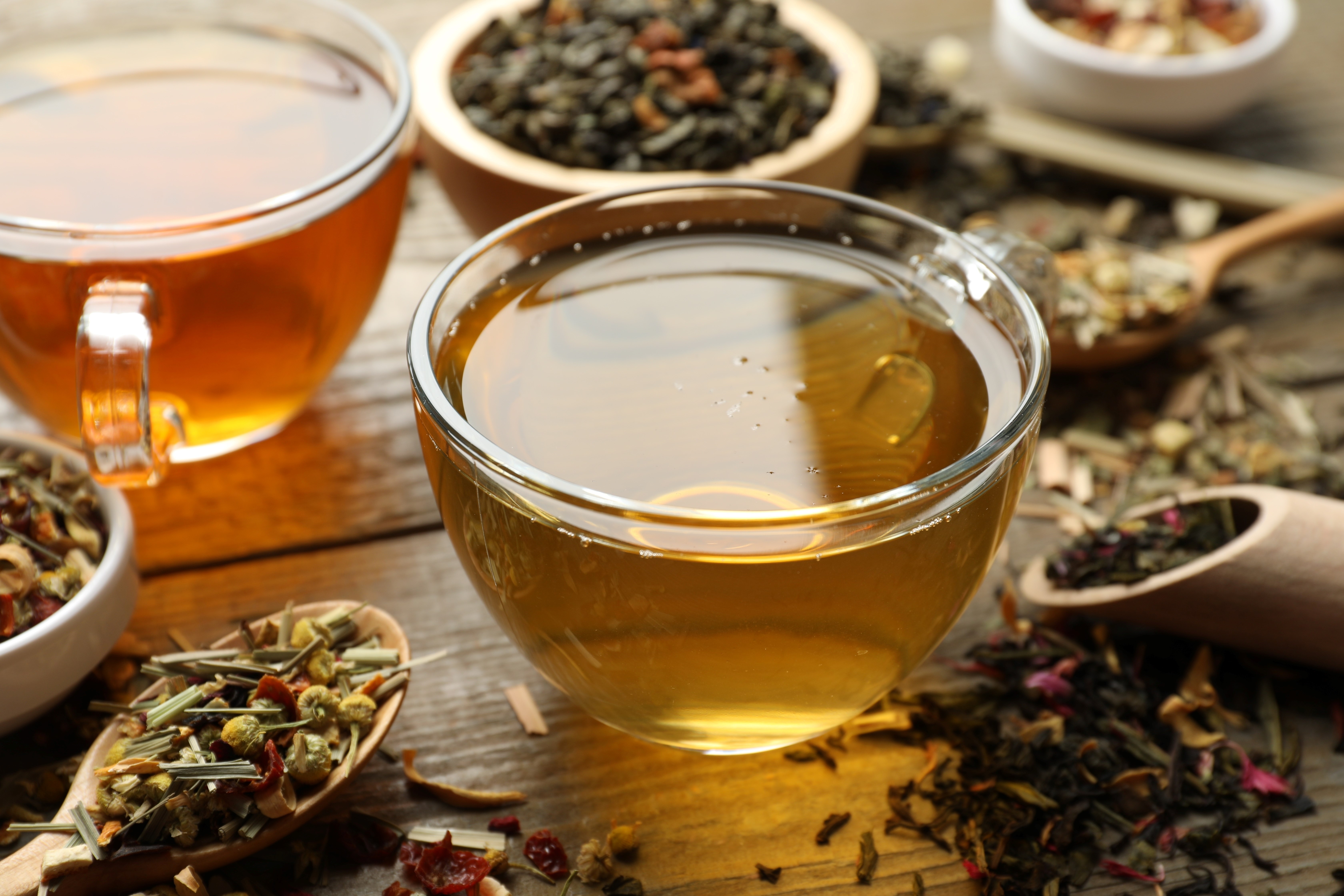 Different herbal teas and dry leaves on wooden table, closeup