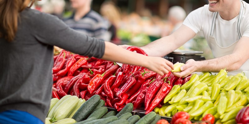 Woman buying fresh organic vegetables at street market.