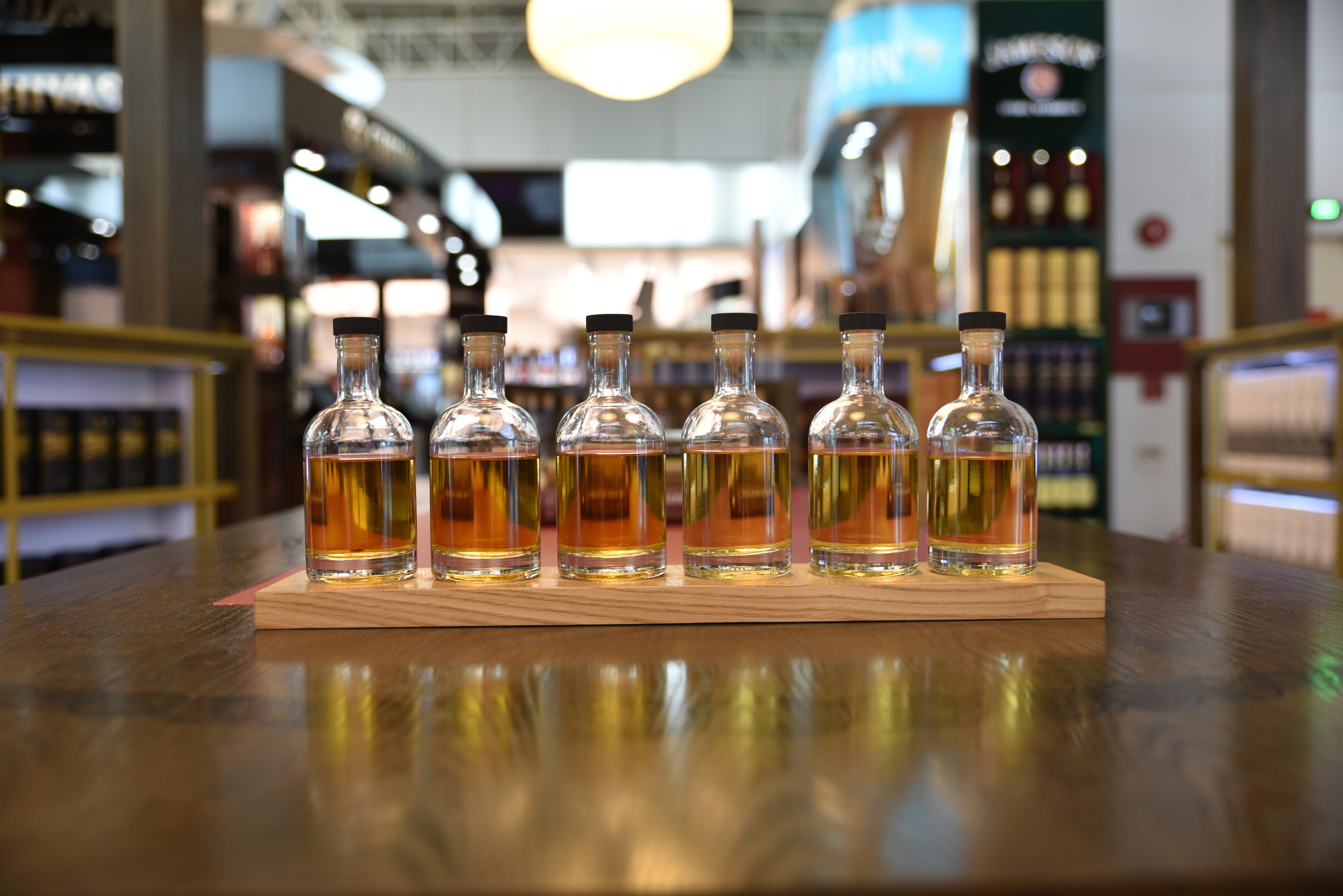 Small Test Alcohol bottles on table with reflection of the bottles on whiny wood top