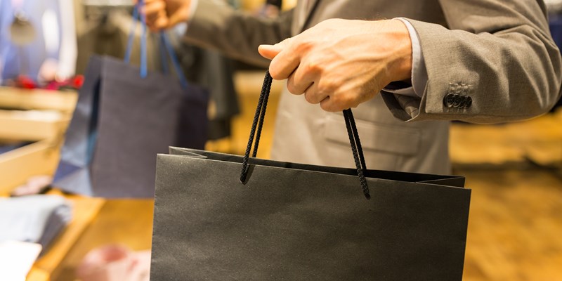 sale, fashion, retail, business style and people concept - close up of man in suit with shopping bags at clothing store