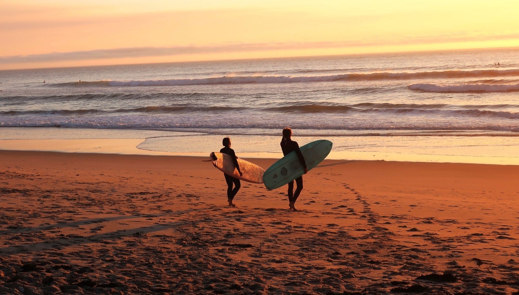 two people going surfing at sunset