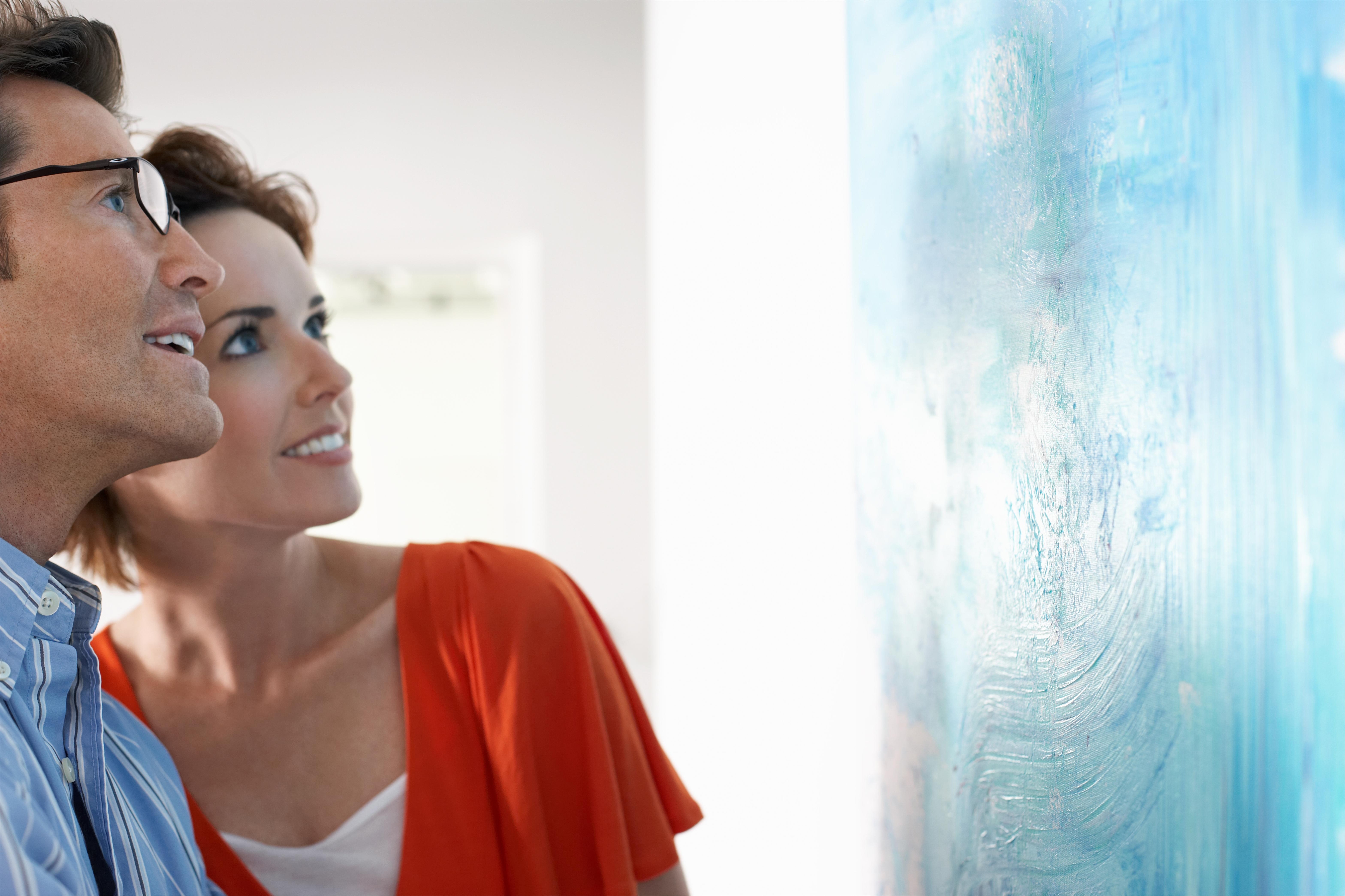 Happy couple looking at modern painting in art gallery