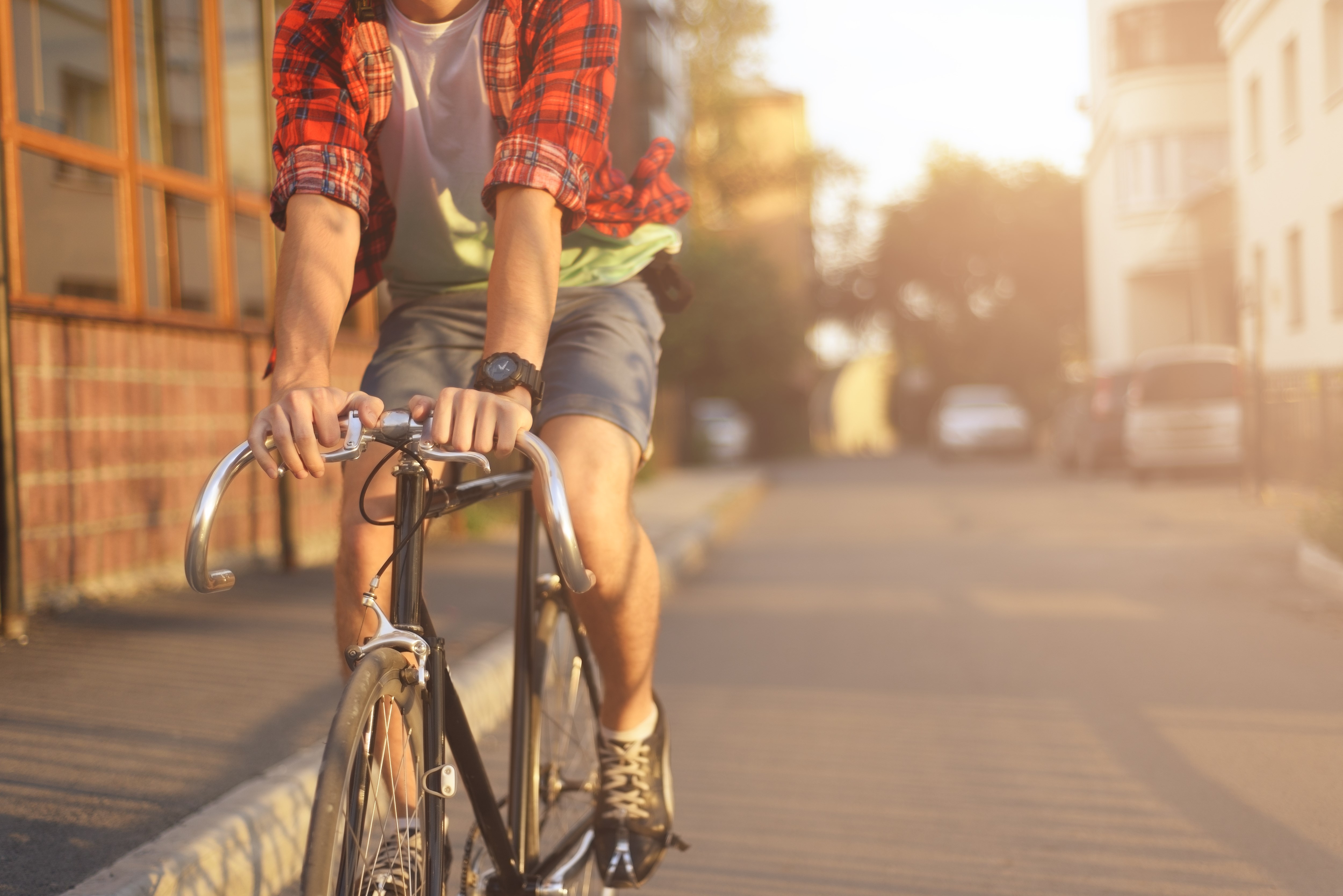 Close up hipster on bike in the city at sunset. Shot with sunflare and without face.