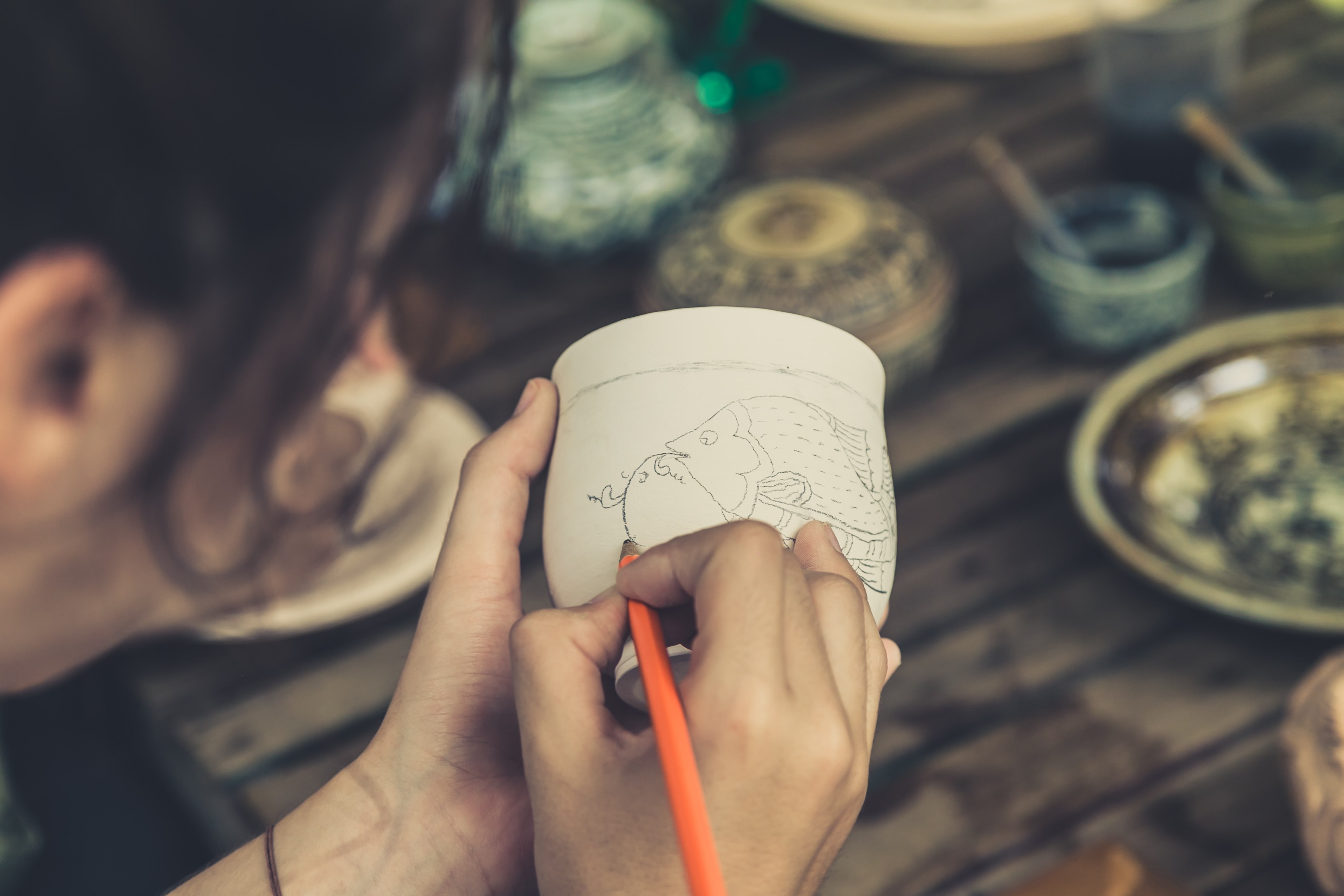 woman painting on a piece of pottery